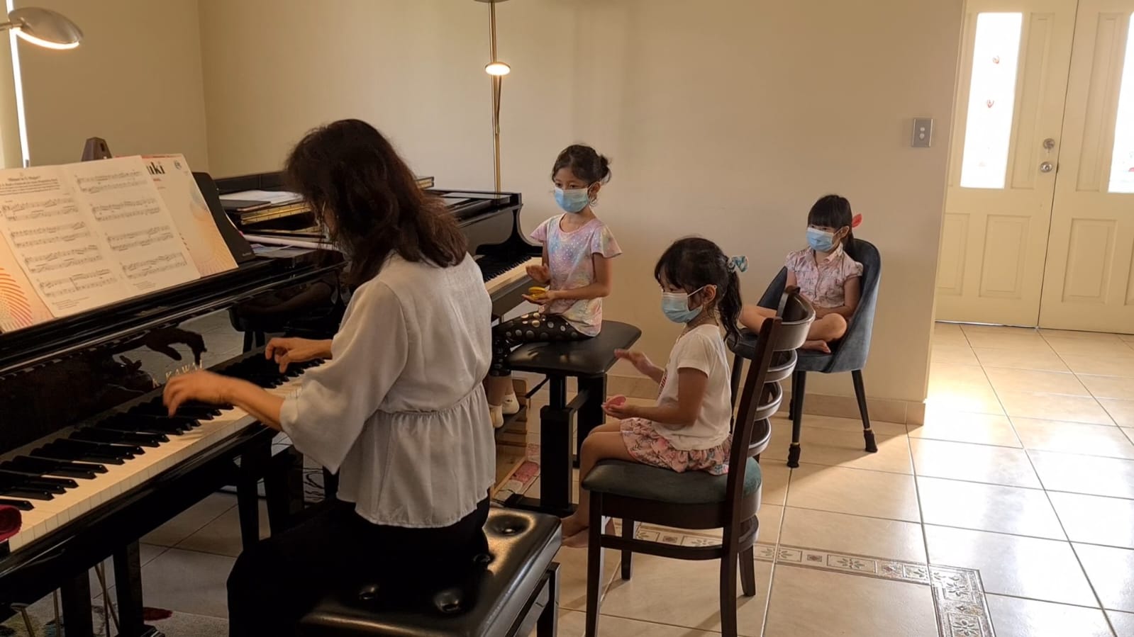 Ms Lien at the grand piano with young students